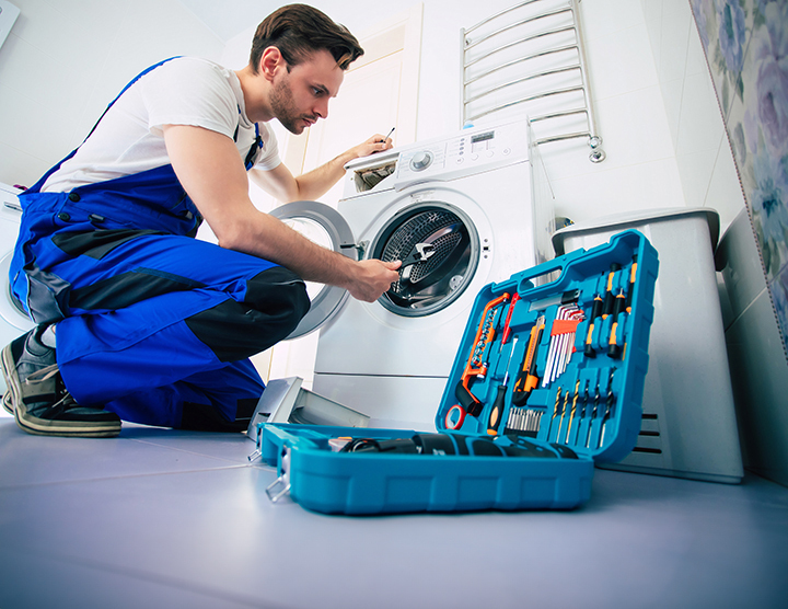 young handsome repairman worker suit with professional tools box is fixing washing machine bathroom
