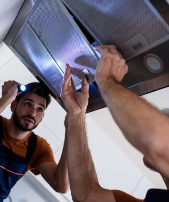 Two person repairing range hood indicating range hood repair services in charlotte nc